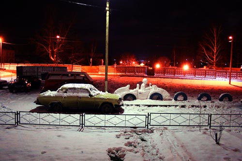 Снежный автомобиль вечером под окном.